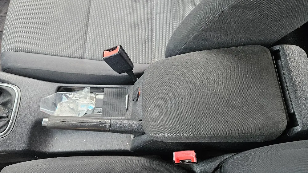 Cotieră centrală textilă gri dintre scaunele din față, înainte de curățarea interiorului auto.
