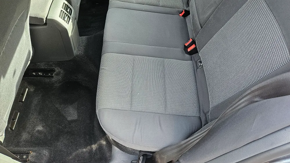 Loc lateral al banchetei auto cu tapițerie gri și zona de podea, văzute după curățare.